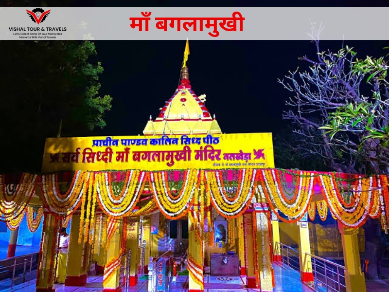 Night view of decorated Maa Baglamukhi Temple entrance with garlands and festive lighting, featuring a banner for Navratri special car rental services from Indore by Vishal Tour & Travels."